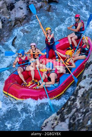 Gruppe von Touristen, die mit dem starken Strom des Gebirgsflusses kämpfen. Stockfoto