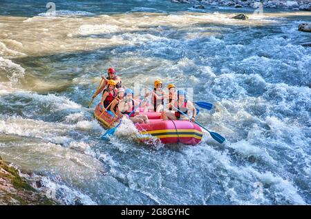 Gruppe von Touristen, die mit dem starken Strom des Gebirgsflusses kämpfen. Stockfoto