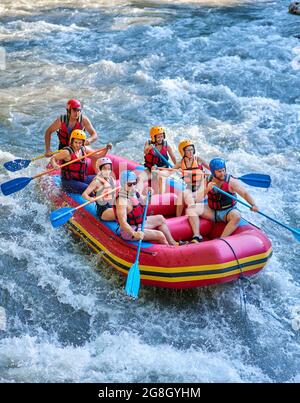 Gruppe von Touristen, die mit dem starken Strom des Gebirgsflusses kämpfen. Stockfoto