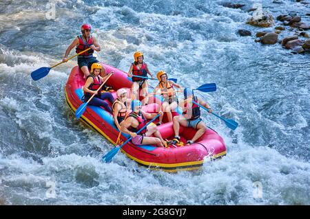 Gruppe von Touristen, die mit dem starken Strom des Gebirgsflusses kämpfen. Stockfoto