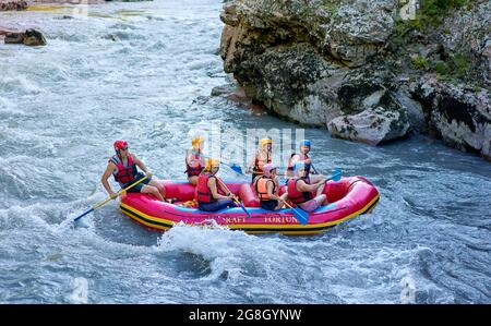 Gruppe von Touristen, die mit dem starken Strom des Gebirgsflusses kämpfen. Stockfoto