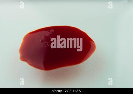 Blutstropfen auf weißer Oberfläche verschmiert. Virus Corona Covid-19 Pandemie Stockfoto