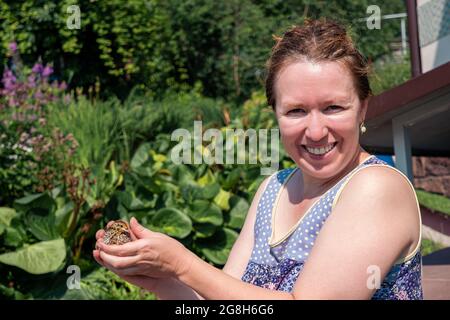 Lächelnde Farmerin hält Wachtelhuhnchen in den Händen im Freien Stockfoto