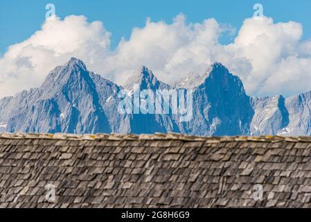 Verwittert und verblasst von der Sonne, Regen und Schnee Holzschindeln, die das Dach eines alpinen Hauses vor dem Hintergrund der hochalpinen Berg sind Stockfoto