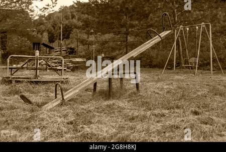 Schwarzweiß-Foto. Alte Schaukeln, verlassene Spielgeräte, auf dem Hintergrund von Schaukeln und Karussells. Stockfoto