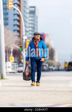 Bärtiger Großvater mit einer Handtasche geht auf der Straße Stockfoto