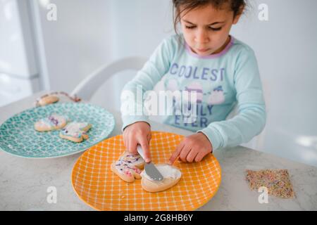 Ein junges Mädchen, das ostereierkekse dekoriert Stockfoto