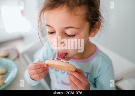 Kleines Mädchen leckt Frosting von ostereierkeks Stockfoto