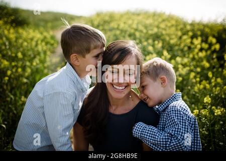 Mutter und Söhne kuscheln im Wildblumenfeld Stockfoto