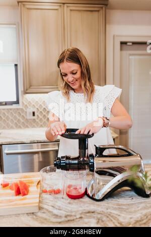 Lächelnde Frau säfelt Obst und Gemüse in ihrer Küche Stockfoto