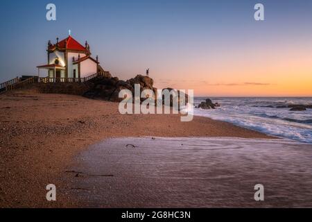 Mann auf einem Felsen mit einem Licht auf der Hand in einer Kapelle am Strand Stockfoto