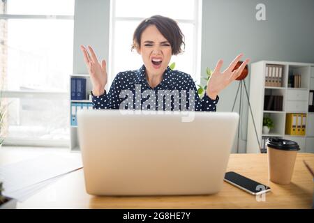 Porträt eines attraktiven verwüsteten verzweifelten Mädchens, das auf einer Web-Konferenz mit Konflikten an der Arbeitsstation in Innenräumen Schimpfungen anrichten musste Stockfoto