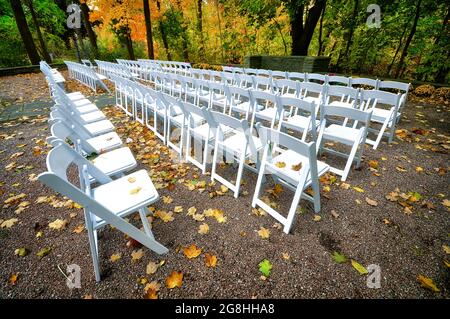 Hochzeitsfeier mit weißen Gartenstühlen im Freien Stockfoto