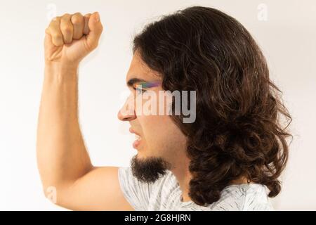 Porträt eines schwulen Mannes in Make-up mit einem Regenbogen, der auf weißem Hintergrund protestiert Stockfoto