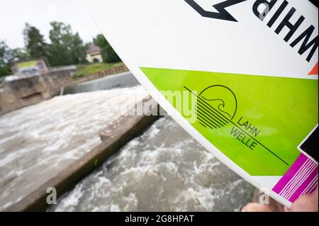 PRODUKTION - 12. Juli 2021, Hessen, Gießen: Ein Mann hält ein Surfbrett mit der Aufschrift 'Lahnwelle' am Wehr, wo die Surfwelle entstehen soll. (An dpa: 'Hessen statt Hawaii: 'Lahnwelle' sollte die Surfszene anziehen') Foto: Sebastian Gollnow/dpa Stockfoto