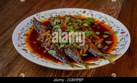 Gebratener Makrele (ikan sardin), gekocht mit würzigem Sambal-Chili und Zwiebeln mit Frühlingszwiebeln als Garnitur. Stockfoto