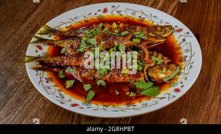 Gebratener Makrele (ikan sardin), gekocht mit würzigem Sambal-Chili und Zwiebeln mit Frühlingszwiebeln als Garnitur. Stockfoto