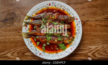 Gebratener Makrele (ikan sardin), gekocht mit würzigem Sambal-Chili und Zwiebeln mit Frühlingszwiebeln als Garnitur. Stockfoto