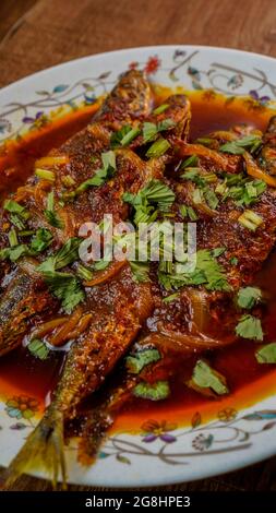 Gebratener Makrele (ikan sardin), gekocht mit würzigem Sambal-Chili und Zwiebeln mit Frühlingszwiebeln als Garnitur. Stockfoto