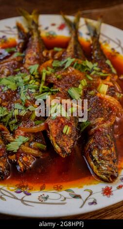 Gebratener Makrele (ikan sardin), gekocht mit würzigem Sambal-Chili und Zwiebeln mit Frühlingszwiebeln als Garnitur. Stockfoto