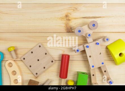 Ein farbenfroher Holzbausatz, ein Roboter für Kinder auf Holz. Set von Werkzeugen auf Holztisch. Spiele und Werkzeuge für Kinder in der Vorschule oder Kindertagesstätte. Natürlich, Stockfoto