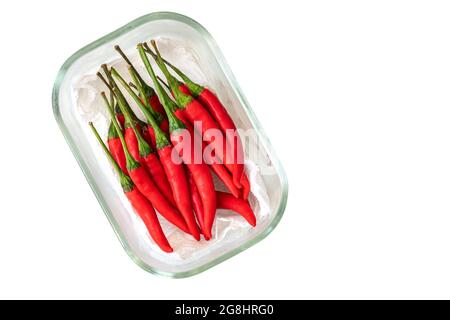 Draufsicht rote Chili oder Jinda Chili aus Thailand. Frische rote Chilischote in einem kleinen Glasbehälter, unterstützt von Küchenhandtuchpapier, isoliertes Bild auf Weiß Stockfoto
