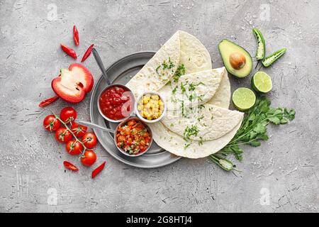 Schalen mit leckeren Salsa-Saucen mit Tortilla und Produkten auf grunge-Hintergrund Stockfoto