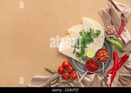 Schalen mit leckeren Salsa-Saucen mit Tortilla auf farbigem Hintergrund Stockfoto