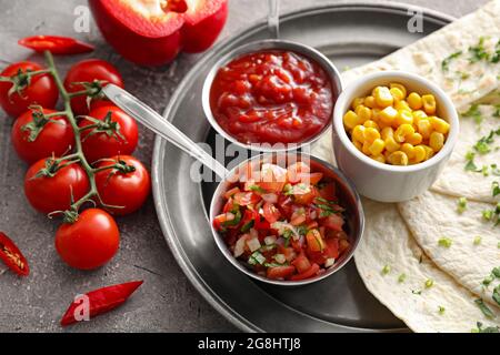 Schalen mit leckeren Salsa-Saucen mit Tortilla und Mais auf grunge Hintergrund Stockfoto