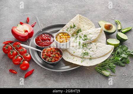 Schalen mit leckeren Salsa-Saucen mit Tortilla und Produkten auf grunge-Hintergrund Stockfoto