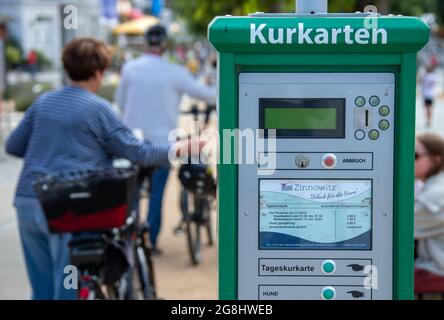 Zinnowitz, Deutschland. Juli 2021. Urlauber schieben ihre Fahrräder an einem Automaten vorbei, um an der Strandpromenade Spa-Tickets auszustellen. Hotels, Pensionen und Campingplätze in Mecklenburg-Vorpommern sind in den kommenden Wochen gut ausgebucht. Nach Angaben des Tourismusverbandes könnte sich die Saison wie im vergangenen Jahr bis in den September erstrecken. Quelle: Jens Büttner/dpa-Zentralbild/dpa/Alamy Live News Stockfoto