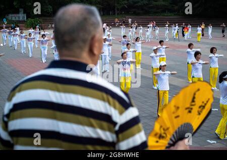 Peking, China. Juli 2021. Ein Mann mit einem Fan sieht Rentner tanzen im Chaoyang Park in Peking, China am 20/07/2021 China rollt Steuererleichterungen und flexiblen Arbeitsurlaub, um Geburten zu fördern. Im Jahr 2020 gab es 12 Millionen Neugeborene, was die niedrigste Zahl von Geburten seit den 1960er Jahren war. Demographen projizieren, dass bis 2050 die über 60-jährige Bevölkerung ein Drittel der countrys-Gesamtbevölkerung ausmachen könnte. Von Wiktor Dabkowski Credit: dpa/Alamy Live News Stockfoto