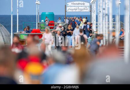 Zinnowitz, Deutschland. Juli 2021. Urlauber und Tagesausflügler sind bei teilweise sonnigem Wetter auf der Seebrücke auf der Ostseeinsel Usedom unterwegs. Hotels, Pensionen und Campingplätze in Mecklenburg-Vorpommern sind in den kommenden Wochen gut ausgebucht. Nach Angaben des Tourismusverbandes könnte sich die Saison wie im vergangenen Jahr bis in den September erstrecken. Quelle: Jens Büttner/dpa-Zentralbild/dpa/Alamy Live News Stockfoto