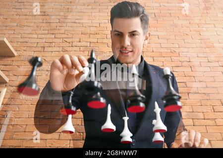 Hübscher Mann, der Schach auf einem Glastisch spielt Stockfoto