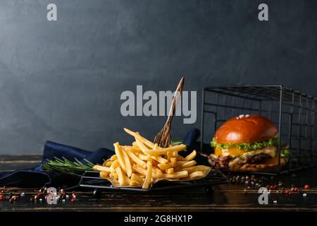 Leckere pommes Frites und Burger auf dunklem Holzhintergrund Stockfoto