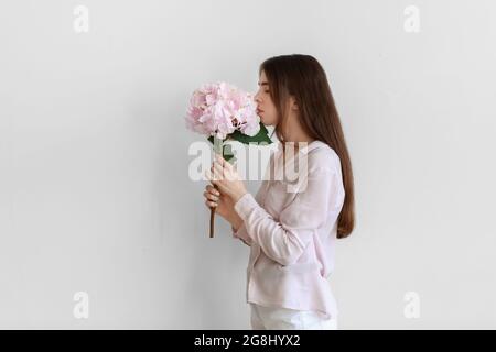 Junge Frau mit Hortensienblüten auf hellem Hintergrund Stockfoto