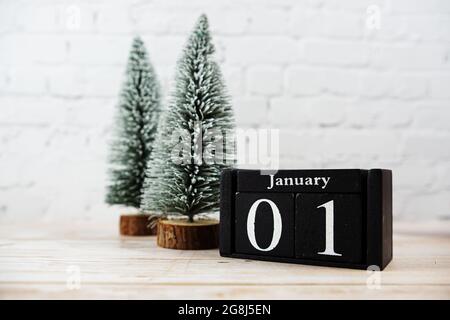 1. Januar auf dem Holzkalender mit kleinem weihnachtsbaum auf weißem Backsteinwand Hintergrund Stockfoto