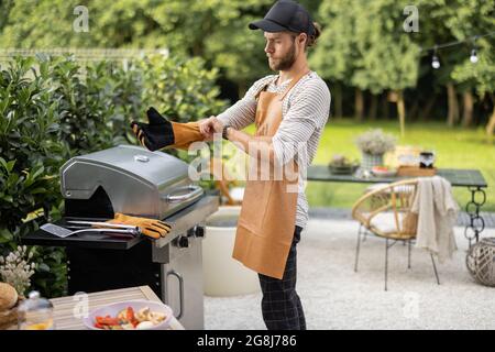 Hübscher Mann, der sich für das Kochen auf dem Grill vorbereitet Stockfoto
