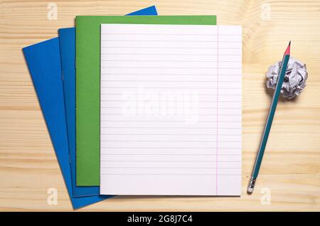 Schulhefte, leeres Blatt, zerknittertes Papier und Bleistift auf Holzschreibtisch, Draufsicht. Platz für Text Stockfoto