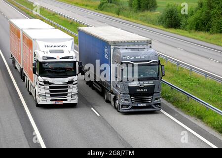 MAN TGX, International Truck des Jahres 2021, überholt vor dem Sattelauflieger den Scania R500 LKW auf der Autobahn. Salo, Finnland. 9. Juli 2021. Stockfoto