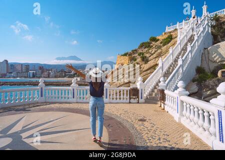 Junge unbeschwerte Touristenfrau mit offenen Armen genießt Sommerurlaub in Spanien. Tourismus in Europa. Berühmter Balcon del Mediterraneo, Benidorm, Spanien Stockfoto