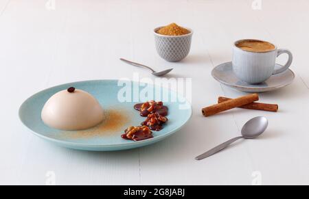 Espresso Panna Cotta mit Walnüssen in Karamell, Tasse Kaffee und Schüssel mit Zuckerrohr. Low-Angle-Ansicht. Stockfoto