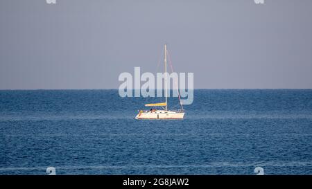 Aberystwyth, Ceredigion, Wales, Großbritannien. 21. Juli 2021 UK Wetter: Der Tag beginnt mit schöneren Sonnenstrahlen, während ein Segler das beruhigende Wasser der Cardigan Bay an der Küste von Aberystwyth, Wales, genießt. © Ian Jones/Alamy Live News Stockfoto