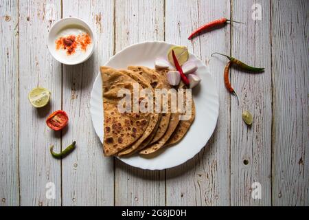 Gefüllte Kartoffel oder Aloo Paratha serviert mit Gewürzen und Quark. Ein indisches Frühstücksgericht. Stockfoto