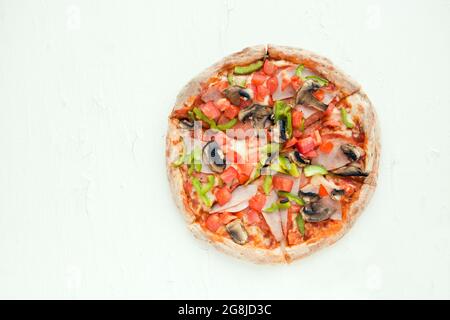 Draufsicht auf italienische Pizza auf weißem Tisch mit Pilzen, Tomaten, Oliven und Käse. Sehen Sie wie Prosciutto, Capricciosa, PIZZA mit Dekoration. Foto mit Stockfoto