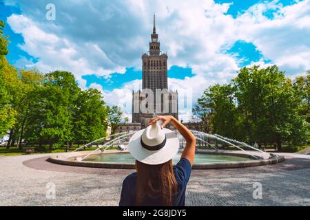 Junge Touristenfrau in weißem Sonnenhut zu Fuß im Park in der Nähe des Kultur- und Wissenschaftspalastes in Warschau, Polen. Urlaub Warschau im Sommer Stockfoto