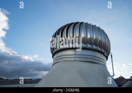 Wolkenblauer Himmel und Dachventilator auf dem Dach der Industriezur natürlichen Kühlung durch natürlichen Wind, selektiven Fokus und Low-Angle-Shot Stockfoto