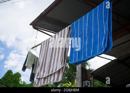 Farbige Handtücher zum Trocknen auf einem Wäscheständer draußen. Frische, saubere Handtücher, die an der Wäscheleine im Freien trocknen. Die Wäsche hängt am Trockner. Gedreht in Chiang Stockfoto
