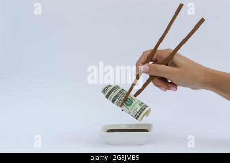 Dollar in einem Holz-Essstäbchen auf einem weißen mit einem Kopierplatz. Stockfoto