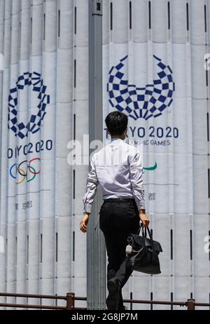 (210721) -- TOKIO, 21. Juli 2021 (Xinhua) -- EIN Mann geht am Logo von Tokio 2020 in der Innenstadt von Tokio, Japan, 21. Juli 2021 vorbei. Die Olympischen Spiele 2020 in Tokio beginnen hier am Freitag. (Xinhua/Liu Dawei) Stockfoto